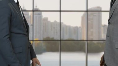 Paralı işadamları takım elbiseli adamların elini sıkıyor.