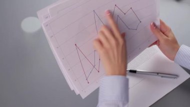 Grafik çizelgelerini tutan kadın elleri grafik çizelgeleri okuyor.