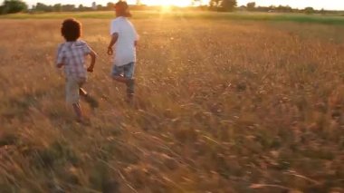 Çocuklar gün batımında koşar. Koşar adım çocuklar.