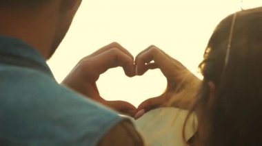 Elleriyle kalp yapan genç çifti kapatın.