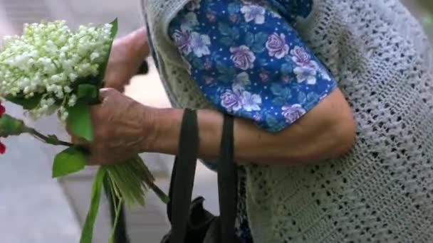 Старая бабушка с цветами в день памяти — стоковое видео