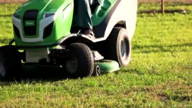 Yeşil çim biçme makinesi traktörü çim biçme hareketini yakından takip ediyor.