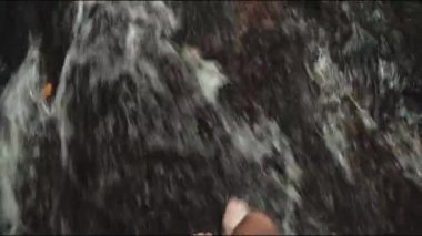 Nehirde yürüyen kişi kayalara basıyor.