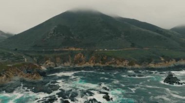 Dağın eteğindeki yol bir su kütlesinin yanında.