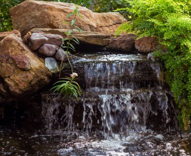 İlkbaharda halka açık bir parktaki gölete küçük bir şelale, TX.