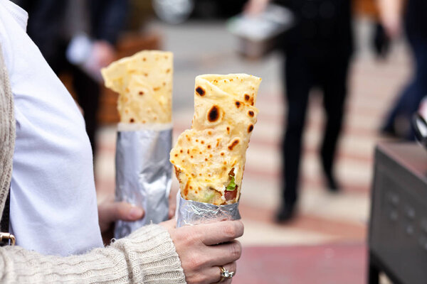 Female hand holding a burrito on a street fajitas, pita bread, shawarma