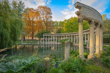 Paris, France - 10 11 2020: Golden hour in Parc Monceau in autumn. Oval basin bordered by a Corinthian colonnade clipart