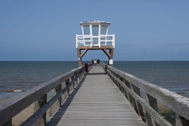 Luc-Sur-Mer, Fransa - 08 05: 2025: Balıkçı İskelesi adlı denizin önündeki ahşap iskele ve mavi gökyüzü arkaplanı