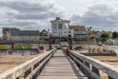 Luc-Sur-Mer, France - 08 05 2025:  View of the wooden pier in front of the coastline with beach houses background