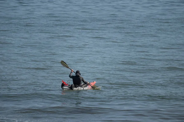 Saint-Aubin-Sur-Mer, France - 08 11 2025: A man in diving suit rows a canoe on the sea