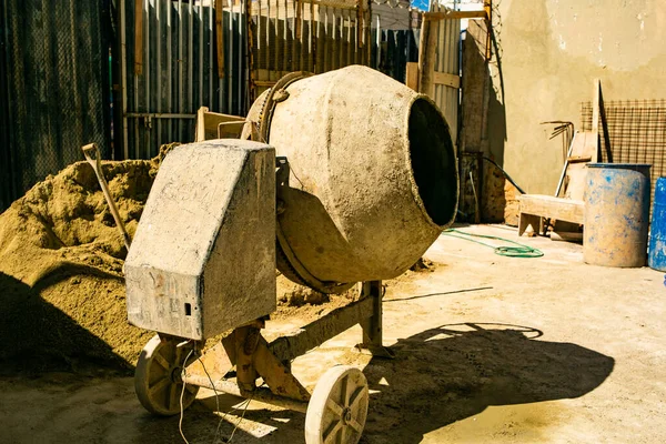 wheel, old, bucket, tool, tire, barrel, dirty, no person, concrete mixer, forge, chair, container, table, cart, automotive tire, sitting, machine, plant, room, small, helmet, industry, area, hardhat, wooden, brick, rusty, living, worker, agricu