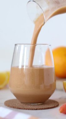 Portakal suyunu bardağa dolduruyorum. Dikey video. Yakın plan..