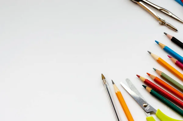 Beyaz arka planda okul malzemeleri renkli kalemler, makas ve kalemle