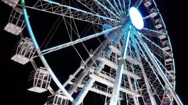 CAGLIARI, SARDINIA, ITALY - 07 Ağustos 2020: Gece gökyüzüne karşı renkli ışıklarla aydınlatılan metalik dönen dönme dolabın düşük açılı görüntüsü - Roman cagliari Ruota panoramica