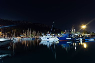Cagliari, Sardinya, İtalya - 28 Ağustos 2020: Bir çok balıkçı teknesi gece limana demirlemiş su yansımaları ile