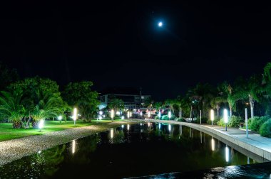 Bir nehir ve yazın güzel ışıkları olan gece parkı, su yansımaları ve ay - Parco della Musica Cagliari