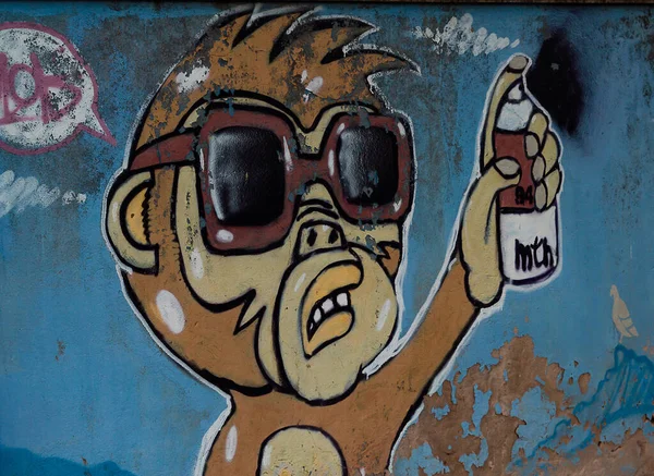 Cagliari, Sardinya, İtalya - 31 Ağustos 2020: Duvarda kırmızı güneş gözlüklü turuncu bir maymun ve bir elinde sprey kutu