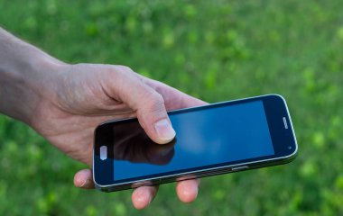 Beyaz adamın elinde cep telefonu var. Arka planı bulanık. Ekranda yansıması var.