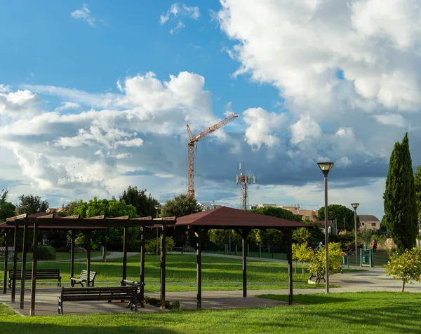 Turuncu kule, mavi gökyüzüne karşı yeşil bir şehir parkından bulutlar görünüyor.