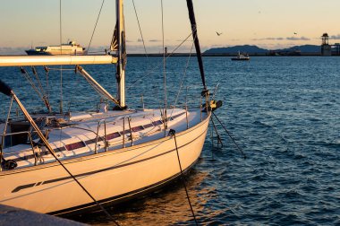 Akdeniz 'de gün batımında iskelede demirli bir tekne ve gökyüzünde martılarla