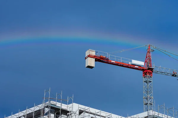 Gökkuşaklı bulutlu gökyüzüne karşı yeni bina vinç ve beton yapı
