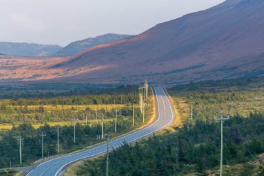 Twisting road running beside the Tablelands in the Gros Morne National Park in Newfoundland, Canada clipart