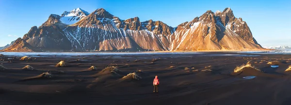 Hiker enjoying sunset at Vestrahorn (Batman Mountain) and its black sand beach in Iceland