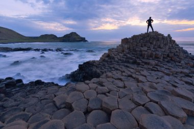 Kuzey İrlanda 'da gün batımında Giant Causeway' de duran bir kişinin silueti. 