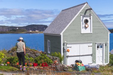 Newfoundland, Kanada 'nın engebeli kıyılarında bahçesini sulayan bir kadın..
