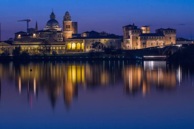 Mantova üzerindeki alacakaranlık silueti İtalya 'daki Lago Inferiore, Lombardy' de yansıdı.
