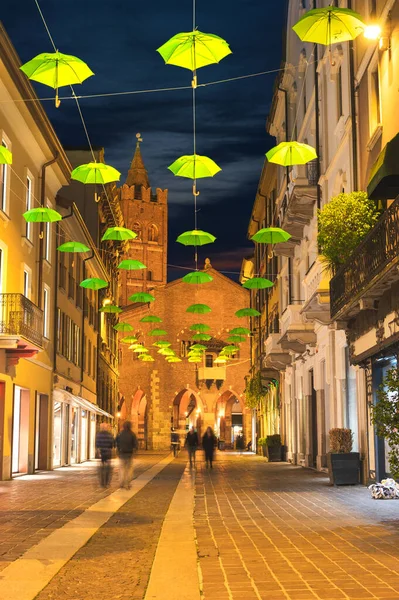 Повешенные зеленые зонтики вдоль главной улицы Монца в сумерках, Ломбардия, Италия — стоковое фото