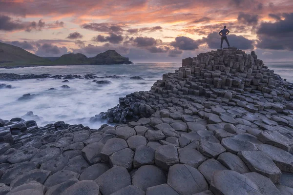 Silhuett av en person som står vid Giant Causeway stenar vid solnedgången i Nordirland — Stockfoto