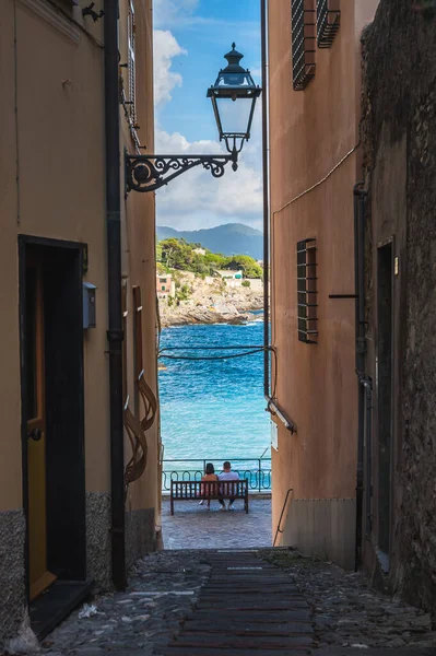 Pareja de jóvenes sentados en un banco frente al mar, Bogliasco, Ligury, Italia — Foto de Stock