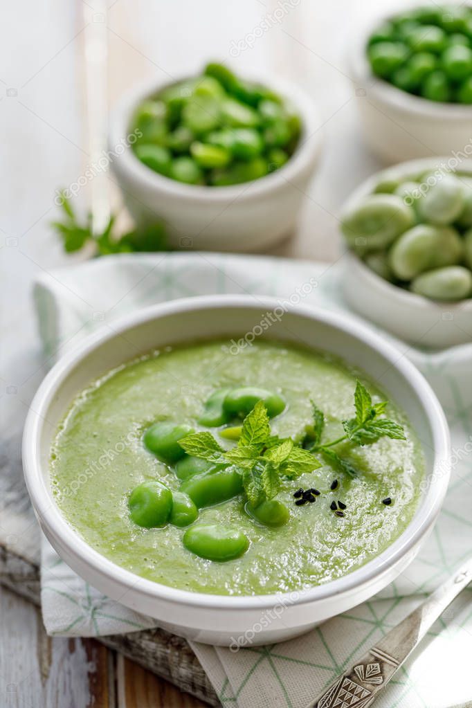 Vegetable cream soup. Broad bean soup sprinkled with  fresh mint and nigella seeds. Delicious and nutritious vegan food. Healthy eating concept.