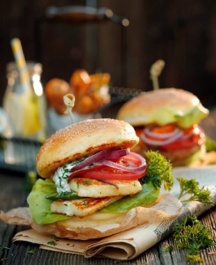 Hellim burger taze marul, domates, salatalık ve yoğurt nane sosu bir ahşap rustik masa üzerinde ilavesi ile soğan ile