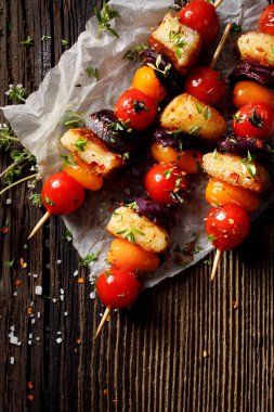 Hellim peyniri, domates, kırmızı soğan ve ahşap rustik masa üzerinde taze otlar ile vejetaryen şişleri görünümü top