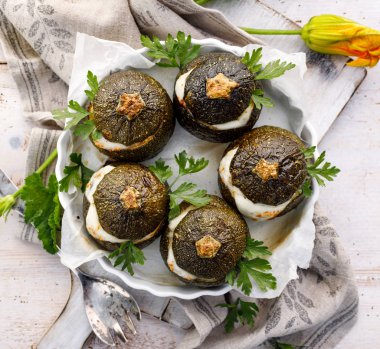 Vejetaryen Kabak dolması. Pişmiş pirinç, mantar ve peynir bir ahşap beyaz masa, üstten görünüm üzerinde bir pişirme çanağı aromatik otlar ilavesi ile doldurulmuş yuvarlak kabak