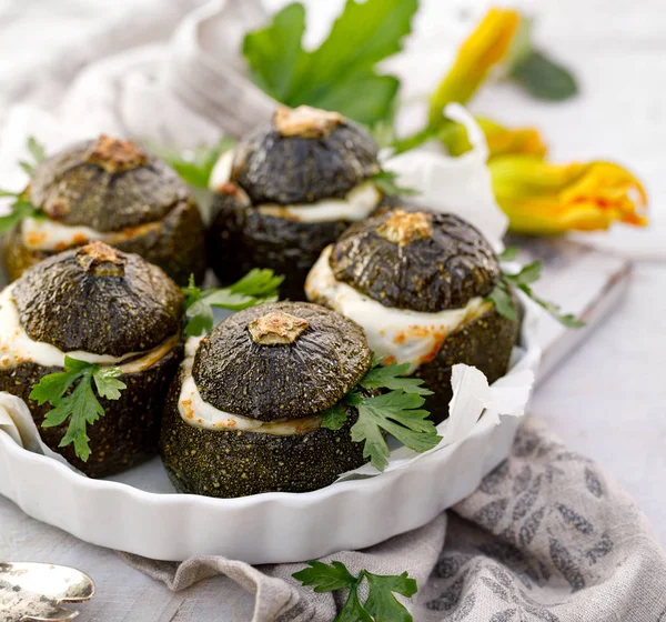 Vejetaryen Kabak dolması. Pişmiş yuvarlak kabak dolması pirinç, mantar ve peynir bir ahşap beyaz masa üzerinde bir pişirme çanağı aromatik otlar ilavesi ile