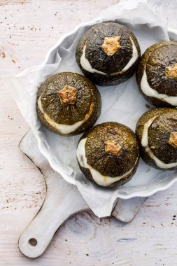 Vejetaryen Kabak dolması. Pişmiş pirinç, mantar ve peynir bir ahşap beyaz masa, üstten görünüm üzerinde bir pişirme çanağı aromatik otlar ilavesi ile doldurulmuş yuvarlak kabak