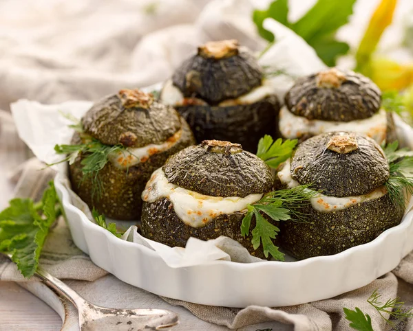 Vejetaryen Kabak dolması. Pişmiş yuvarlak kabak dolması pirinç, mantar ve peynir bir ahşap beyaz masa üzerinde bir pişirme çanağı aromatik otlar ilavesi ile