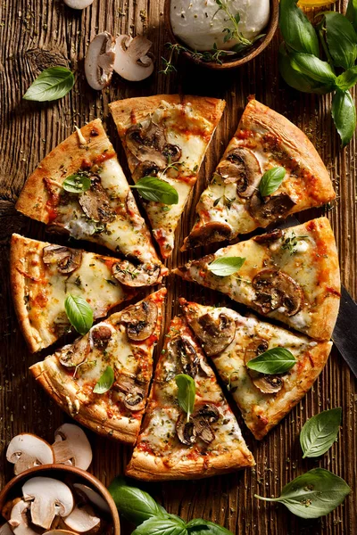 Mushroom pizza with addition mozzarella cheese and herbs on a wooden table, top view. Pizza slice Pizza slice