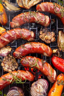 Grilled sausages and vegetables with addition spices and fresh herbs on a grill plate, top view. Barbecue grill, grilled food, bbq clipart