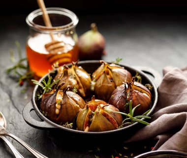 İncir Dolması gorgonzola peyniri, çam fıstığı, bal ve otlar bir karanlık siyah bir tabak içinde pişmiş, arka plan, üstten görünüm taş. Mükemmel, lezzetli, vejetaryen yemek, meze