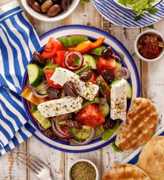 Greek salad. Traditional Greek salad consisting of fresh vegetables such as tomatoes, cucumbers, peppers, onions, oregano and olive oil, top view. A delicious and healthy vegetarian, mediterranean dish