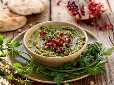 Humus. Nar tohumları, maydanoz, zeytinyağı ve ahşap bir paslı masa üzerinde seramik bir tencerede aromatik baharat ilavesi ile bitkisel humus. Bir sağlıklı ve lezzetli vejetaryen yemek, bir türlü Yapıştır, yaymak, DIP