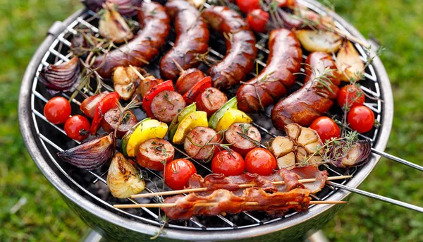 烤的食物 各种烧烤产品 烤香肠 肉类和蔬菜串 培根和蔬菜在烤盘上 烧烤架 — 图库照片