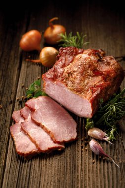 Füme etler, taze otlar ve aromatik baharat ilavesi ile ahşap bir masa üzerinde füme Domuz loin dilimlenmiş.  