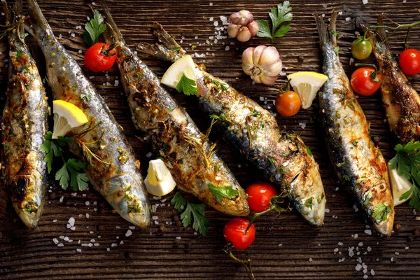 Fried fishes with addition of herbs, spices and lemon slices on a wooden background, top view. — Stock Image Fried Fishes Addition Herbs Spices Lemon Slices Wooden Background Top Stock Photo