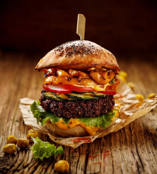 Vegan burger, beetroot burger, homemade burger with beetroot cutlet, grilled bell pepper, zucchini, radish, fresh lettuce and aromatic curry sauce on a rustic wooden background. Healthy eating concept