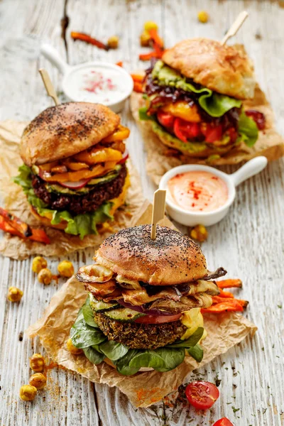 Veggie burgers, homemade vegan burgers with fresh and grilled vegetables and aromatic  sauces on a white rustic table. Conception of a healthy diet, healthy alternative